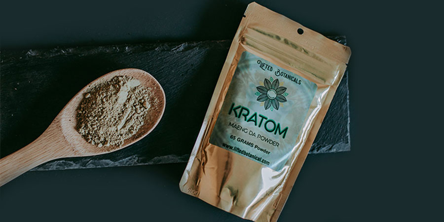wooden spoon with kratom powder and a kratom powder in gold packaging